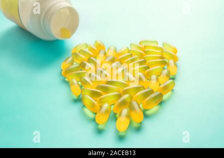 Große medizinische Kapseln und Tabletten - Vitamine und Zusatzstoffe auf blauem Hintergrund liegen in der Form eines Herzens. Kopieren Sie Platz. Close Up. Selektiver Fokus Stockfoto