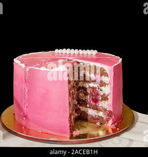 Köstliche rosa Hoch geschichteten Kuchen für die Taufe oder Geburtstag. Schneiden Sie ein Stück Kuchen. Auf schwarzem Hintergrund isoliert. Stockfoto
