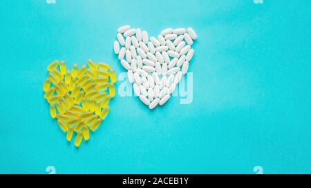 Große medizinische Kapseln und Tabletten - Vitamine und Zusatzstoffe auf blauem Hintergrund liegen in der Form eines Herzens. Kopieren Sie Platz. Close Up. Selektiver Fokus Stockfoto