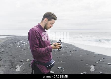 Mann mit Kamera am Strand in Island Stockfoto