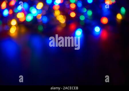Verschwommen bokeh christmas lights in Blau, Rot, Gelb, Orange und Grün auf dunklem Hintergrund Stockfoto