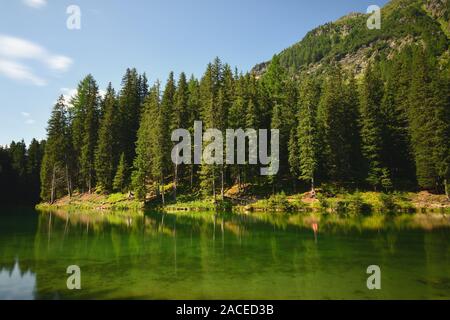 Smaragdgrüne Wasser von einem alpinen See im Wald. Das kristallklare Wasser des schönen See Schwarzwassersee in der Nähe von Ischgl, Paznaun, Tirol, Österreich. Stockfoto