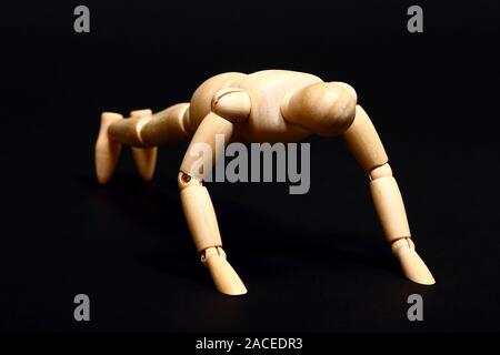 Konzeptionelle Bild von einer hölzernen Puppe, Push-ups auf schwarzem Hintergrund Stockfoto