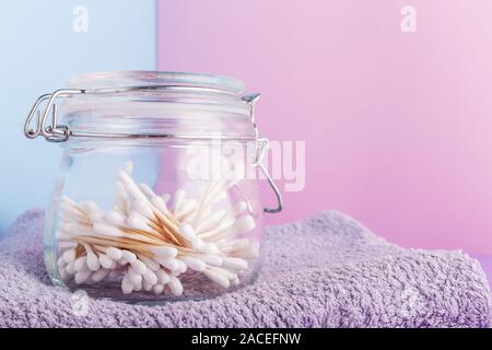 Reinigungsstäbchens Putzlappen in einem Glas auf farbigen Hintergrund. natürliche Pflegeprodukte. Biologisch abbaubare Holz- Wattestäbchen. Natürliche Pflegeprodukte. Umweltfreundlich Stockfoto