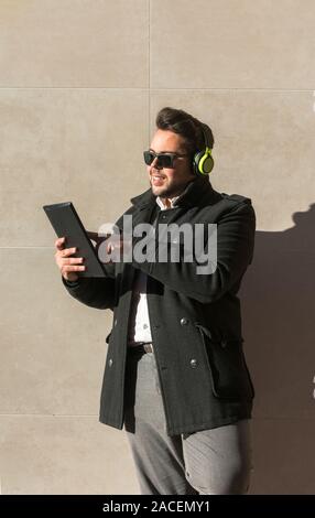 Foto von einem jungen Mann, während er seine Tablette ist gerade auf der Straße Stockfoto