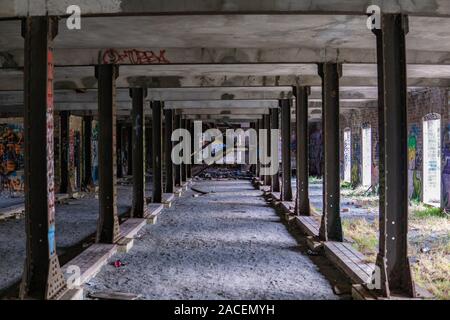 Zeilen aus Metall Säulen führt zu einer Treppe in verlassenen Gebäude Stockfoto