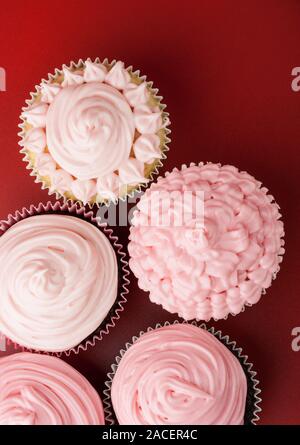 Top Blick auf Nizza Cupcakes mit rosa Zuckerguss, roter Hintergrund Stockfoto