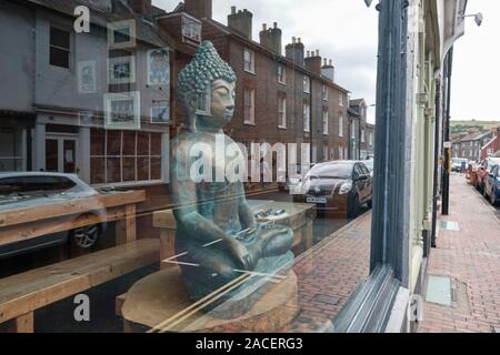 Bild von Buddha in einem Schaufenster mit Reflexionen von Häusern und Autos von der Straße. Die Statue ist Grün und von guter Größe Stockfoto