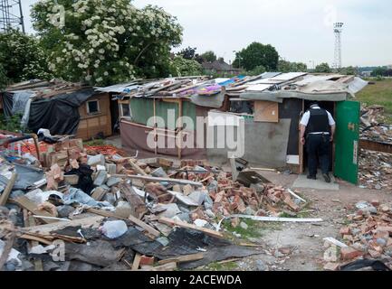 Polizei- und Beamte der Agentur, die Räumung von rumänischen Einwanderer aus einem Elendsviertel auf einem verlassenen Ort an der ehemaligen Hendon United Football Ground in North West London gebaut. Stockfoto