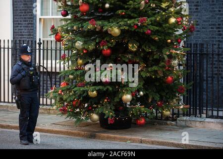 London, Großbritannien. 2. Dezember, 2019. Ein Polizist steht neben einem Weihnachtsbaum von Dartmoor außerhalb Downing Street 10. Es wurde von der Familie business Dartmoor Weihnachtsbäume geliefert, nachdem Sie der Champion Züchter Preis in einen jährlichen Wettbewerb gewonnen. Credit: Mark Kerrison/Alamy leben Nachrichten