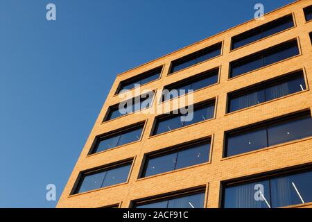 Äußere Low Angle View eines modernen Bürogebäudes mit einer Fassade aus Backstein arbeitet und große Fenster. Stockfoto