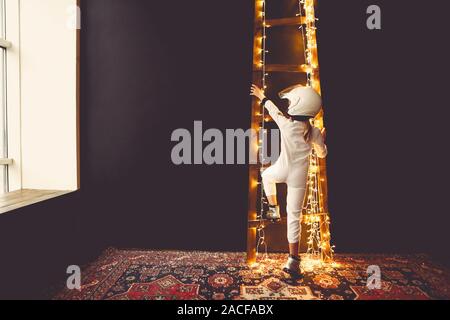 Astronaut futuristische kid Mädchen mit weißen voller Länge einheitliche und Helm tragen Silber Schuhe durch die Treppe Stockfoto