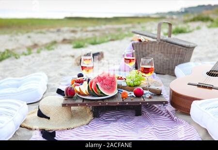 Picknick am Strand bei Sonnenuntergang im Stil von Boho. Essen und Trinken, Entspannen, urlaub Konzept Stockfoto
