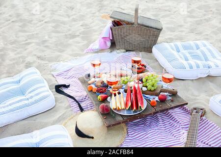 Picknick am Strand bei Sonnenuntergang im Stil von Boho. Essen und Trinken, Entspannen, urlaub Konzept Stockfoto