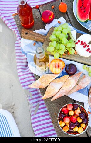 Picknick am Strand bei Sonnenuntergang im Stil von Boho. Essen und Trinken, Entspannen, urlaub Konzept Stockfoto