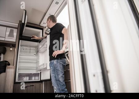 Gebrochene RV Camper Travel Trailer Kühlschrank. Kaukasische Techniker repariert das Gerät innen modernes Freizeitfahrzeug versuchen. Stockfoto