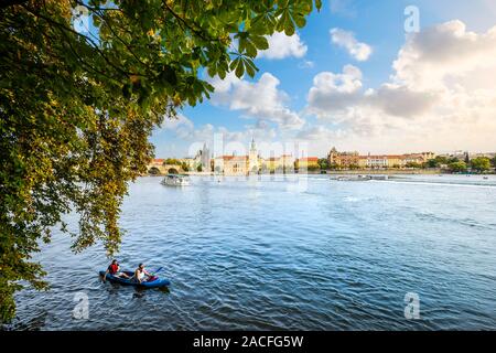 Zwei Männer genießen Sie einen Nachmittag auf der Moldau in Prag in einem blauen Kajak mit der Altstadt im Hintergrund an einem sonnigen Nachmittag im frühen Herbst Stockfoto