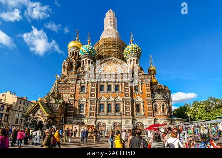 Touristen mischen sich auf dem Platz vor der mittelalterlichen Zwiebeltürmen und Fassade der Kirche des Erlösers auf verschüttetem Blut in St. Petersburg, Russland. Stockfoto