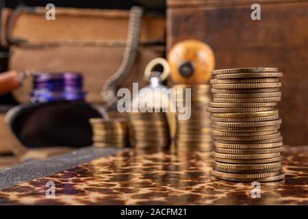 Münzen in Bars auf einem alten Buch angeordnet. Arbeitsplatz ein Buchhalter in einem alten Unternehmen. Der dunkle Hintergrund. Stockfoto