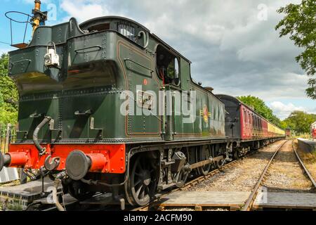 CRANMORE, ENGLAND - Juli 2019: Dampfmaschine und Zug von Wagen warten Cranmore Station auf der East Somerset Railway zu fahren. Stockfoto