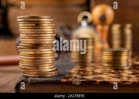 Münzen in Bars auf einem alten Buch angeordnet. Arbeitsplatz ein Buchhalter in einem alten Unternehmen. Der dunkle Hintergrund. Stockfoto