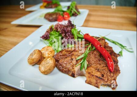 Restaurant speisen. Grillen von Steaks. Reisgericht mit Fleisch auf dem Teller hinzufügen mit Pilzen, Salat und Paprika Stockfoto