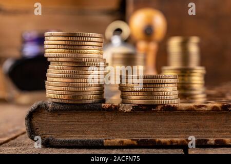 Münzen in Bars auf einem alten Buch angeordnet. Arbeitsplatz ein Buchhalter in einem alten Unternehmen. Der dunkle Hintergrund. Stockfoto