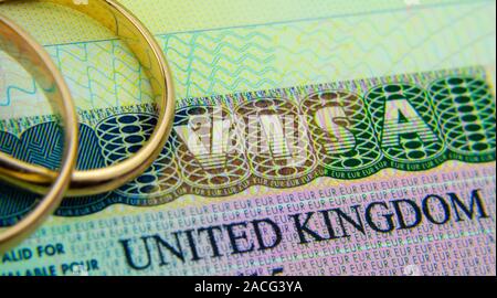 UK Visum Aufkleber in einem Pass und die Ringe oben platziert. Konzept für Partner und Ehepartner Visum GROSSBRITANNIEN. Stockfoto