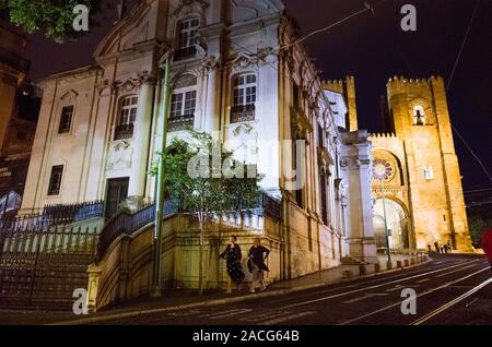 Lissabon, Portugal: zwei Frauen an der Kathedrale von Lissabon bei Nacht beleuchtet und im Jahre 1147 an der Hauptstrasse von Baixa, Alfama Viertel gebaut. Stockfoto