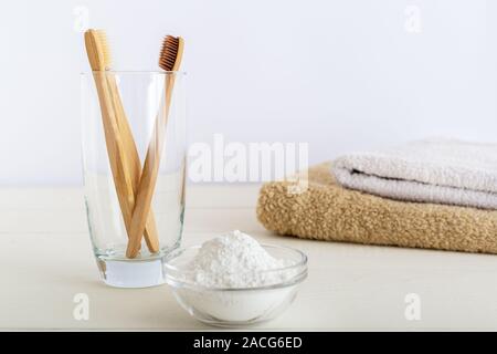 Bambus Zahnbürsten, dentifrice Zahn Pulver auf weißem Hintergrund witn Handtücher aus Baumwolle. Biologisch abbaubaren natürlichen Bambus Zahnbürste. Umweltfreundliche, Null Abfall Stockfoto