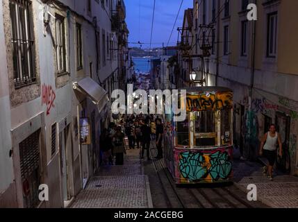 Graffiti bedeckt Lissabon Standseilbahn mit Menschen feierten auf den Straßen der Stadtviertel Bairro Alto auf dem Hintergrund. Stockfoto