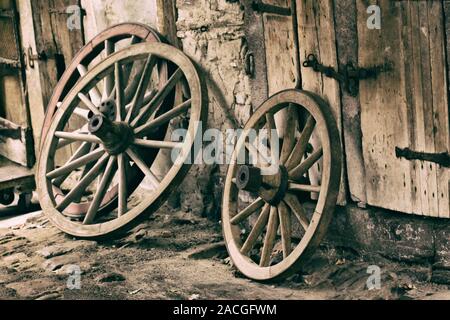 Drei vintage Holz Schlitten Räder lehnte sich an der Wand der Scheune. Stockfoto