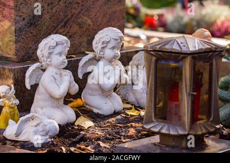 Kleine im Alter von weißem Alabaster Engel Engel Statuen beten vor einem prave Lampe auf dem Friedhof. Stockfoto