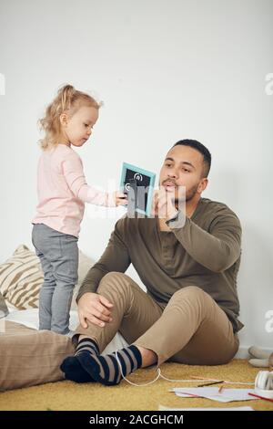 Volle Länge Portrait von niedlichen kleinen Mädchen mit gerahmten Familie Foto zu Papa, kopieren Raum Stockfoto