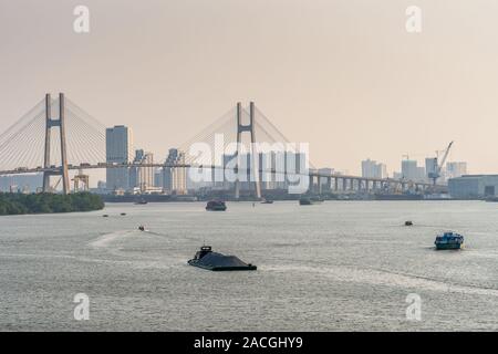 Ho Chi Minh City, Vietnam - 13. März 2019: Sonnenuntergang Himmel geschossen über Song Sai Gon River. Teil von Phu My Brücke mit lastkähnen vor und skyscra Stockfoto