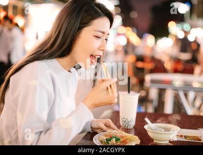 Asiatische Frau genießen bubble Milch Tee mit Street Food in der Nacht Markt Stockfoto