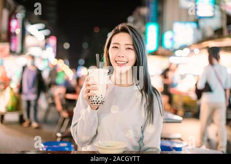 Asiatische Frau genießen bubble Milch Tee mit Street Food in der Nacht Markt Stockfoto