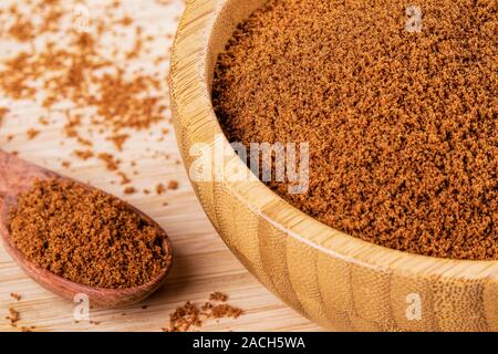 Hölzerne Schüssel voller dunkler brauner Zucker mit einem Kochlöffel auf einen hölzernen Hintergrund Stockfoto