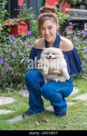 Frau Hug mit pomeranian Hund im Garten Stockfoto