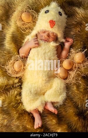Neugeborenes im Huhn Kostüm schlafen auf einem Fell Bett Stockfoto