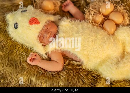 Neugeborenes im Huhn Kostüm schlafen auf einem Fell Bett Stockfoto