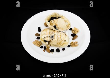 Pita Tasche Brot gefüllt mit Karamell-eis, Walnüsse, Mandeln und Rosinen (getrocknete schwarze Trauben), bereit zu essen, auf schwarzem Hintergrund Stockfoto