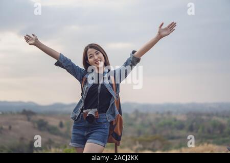 Reisende Frau mit Rucksack stehend mit erhobenen Armen Stockfoto