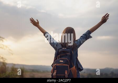 Reisende Frau mit Rucksack stehend mit erhobenen Armen Stockfoto