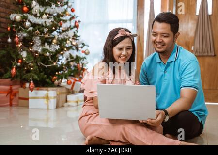 Asiatische Paar mit Laptop am Weihnachtstag Stockfoto