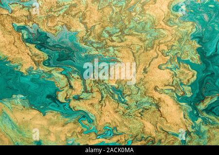 Acryl Flüssigkeit Art Abstrakte goldene Wellen auf grünem Hintergrund mit goldenen Einschlüssen. Frei fließende Farbe. Stockfoto