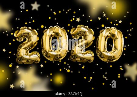 Goldene Zahlen 2020 aus Folie Luftballons, die auf schwarzen Raum glänzenden Sternen. Weihnachten und Neujahr Konzept. Stockfoto