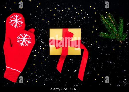 Geschenk gold Box mit rotem Satin und rote Handschuhe mit Christmas tree branch Bug auf dem schwarzen Hintergrund mit vielen kleinen Sterne. Stockfoto