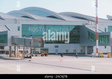 Blick auf den Flughafen Gebäude aus der Schürze. Boden Arbeiter und Maschinen, die in den Arbeitsprozess. Russland, Rostow-am-Don, Platov Flughafen, 2019-04-10 Stockfoto