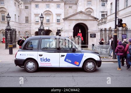 London black cab, mit Tide aktuelle Konto Werbung, stoppte an fußgängerampel vor Royal Guard Post. London, UK, 21. November 2019 Stockfoto